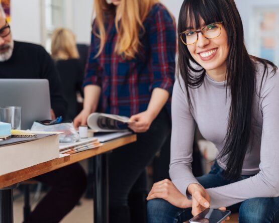 Frau sitzt auf einem Sessel mit Blick in die Kamera