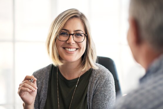 Frau sitzt auf einem Schreibtischsessel mit Blick in die Kamera